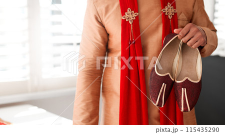 Indian, wedding and clothes for attire of shoes for groom, culture and traditional in color and choice. Stylish, fashion and suit for person in morning for marriage, selection and accessory by tailor 115435290