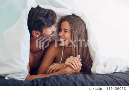 Couple, smile and under blanket in bed for morning romance, love and bonding on weekend. Relationship, man and woman laying together in home for comfort, relax or care and playing with partner 115436058