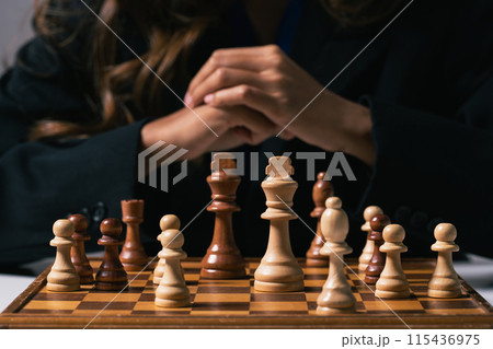 Businesswoman with hands clasped making decisions with calm and collected demeanor in front of chess board Businesswoman with hands clasped making decisions with calm and collected demeanor in front of chess board 115436975