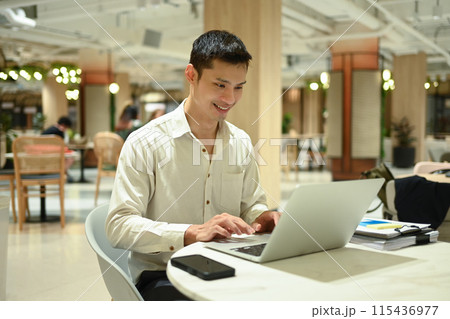 Professional businessman using laptop in a vibrant coworking open space with plant Professional businessman using laptop in a vibrant coworking open space with plant 115436977