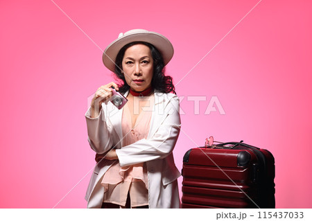 Senior woman with travel accessories on pink background. Summer, travel and vacation concept 115437033