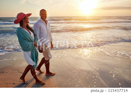 Happy couple, beach and walking in sunset with love for summer holiday, vacation or travel. Young people holding hands for anniversary or valentines day by ocean waves and sand for romance in mock up 115437714