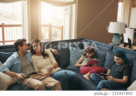 Family, children and parents on couch, watching tv or streaming on tablet with bonding in living room. Mother, father and kids with electronics, popcorn or movies to relax with show on sofa at house 115437893