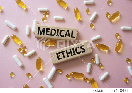 Medical Ethics symbol. Concept word Medical Ethics on wooden blocks. Beautiful pink background with pills. Medicine and Medical Ethics concept. Copy space 115438471