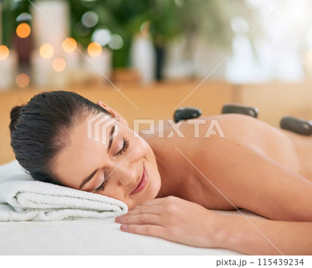 Back, face and hot stone massage with woman in spa to relax for health, peace or wellness. Beauty, calm and stress relief with body of customer in clinic or salon for natural healing treatment 115439234