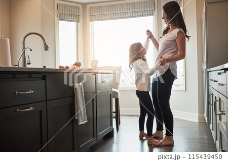 Mother, daughter and dancing in kitchen, happiness and love in house, care and feet of kid on mom. Home, fun and smile for bonding in apartment, teaching and morning for support and holding hands 115439450