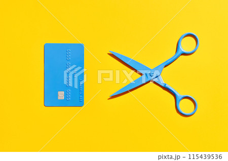 Blue scissors and credit card over yellow background 115439536
