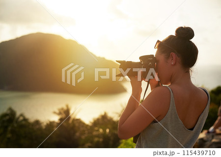Sunset, photography and woman in nature shooting with camera, tech or memory of travel on island. Creative, photographer and cinematic recording of sea, ocean or environment with content creator 115439710