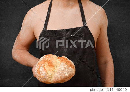 Bread in the hand of a male chef on a black background. Concept of cooking, cooking Bread in the hand of a male chef on a black background. Concept of cooking, cooking 115440040