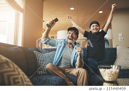 Television, popcorn and man with child in celebration for network, streaming and bonding at home. Dad, son and excited with tv remote in fist for sports, winning and watching live broadcast together Television, popcorn and man with child in celebration for network, streaming and bonding at home. Dad, son and excited with tv remote in fist for sports, winning and watching live broadcast together 115440409