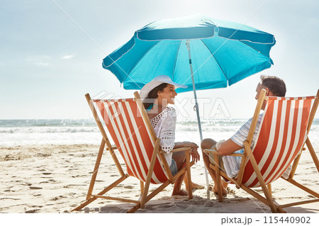 Couple, relax and beach chairs with umbrella on sand for vacation, holiday or weekend break. Summer, man and woman together in nature with water for peace, travel or tourism in Bali getaway with view 115440902