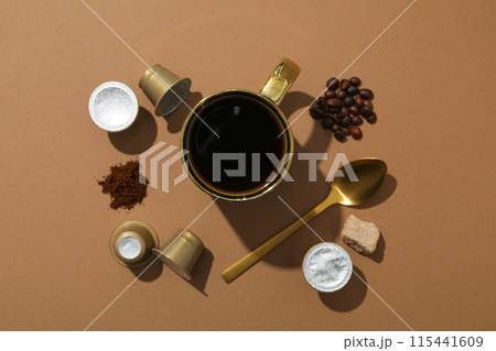 Coffee capsules and beans, sugar, cup with spoon on brown background, top view Coffee capsules and beans, sugar, cup with spoon on brown background, top view 115441609