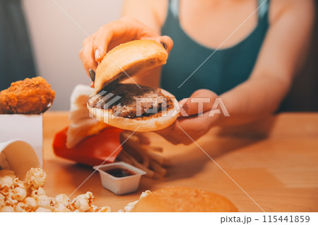 fast food, people and unhealthy eating concept - close up of woman hands holding hamburger or cheeseburger fast food, people and unhealthy eating concept - close up of woman hands holding hamburger or cheeseburger 115441859