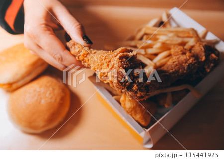 close up focus woman hand hold fried chicken for eat,girl with fast food concept close up focus woman hand hold fried chicken for eat,girl with fast food concept 115441925