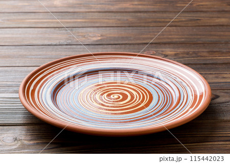 Perspective view of empty colorful plate on wooden background. Empty space for your design 115442023
