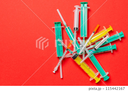 Top view of a heap of syringes and insulin syringes at red background. Medical injection concept with copy space 115442167