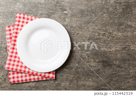 Top view on colored background empty round white plate on tablecloth for food. Empty dish on napkin with space for your design 115442319