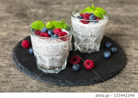 Healthy breakfast or morning with chia seeds vanilla pudding raspberry and blueberry berries on table background, vegetarian food, diet and health concept. Chia pudding with raspberry and blueberry 115442349