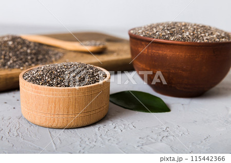 Chia seeds in bowl and spoon on colored background. Healthy Salvia hispanica in small bowl. Healthy superfood Chia seeds in bowl and spoon on colored background. Healthy Salvia hispanica in small bowl. Healthy superfood 115442366