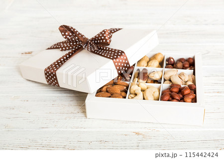 Various varieties of nuts lying in paper box on table background. Top view. Healthy food. Close up, copy space, top view, flat lay. Walnut, pistachios, almonds, hazelnuts and cashews 115442424
