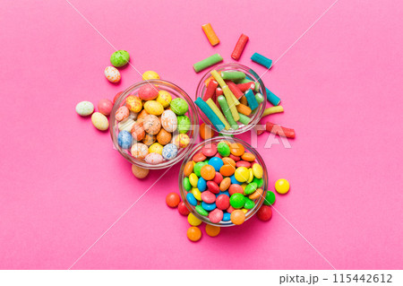 different colored round candy in bowl and jars. Top view of large variety sweets and candies with copy space different colored round candy in bowl and jars. Top view of large variety sweets and candies with copy space 115442612