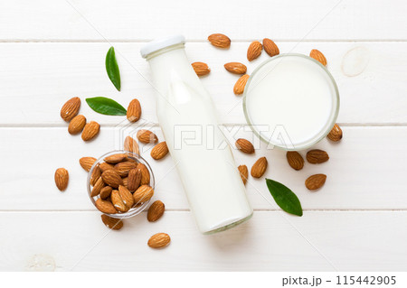 Top view of the almond milk in the glass bottle with almond nuts on the colored table. top view vith copy space Top view of the almond milk in the glass bottle with almond nuts on the colored table. top view vith copy space 115442905