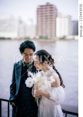 川沿いで笑っている新郎新婦 115443030