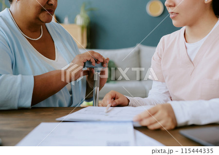 Young nurse explaining rules of filling out form to African American elderly woman Young nurse explaining rules of filling out form to African American elderly woman 115444335