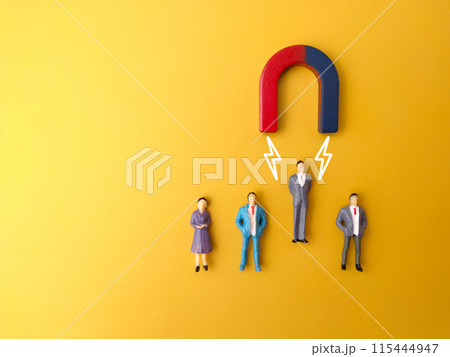 One of miniature people attracts by magnet on a yellow background. Business concept 115444947