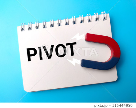 Top view notebook and attracts magnet with text PIVOT on blue background. Top view notebook and attracts magnet with text PIVOT on blue background. 115444950