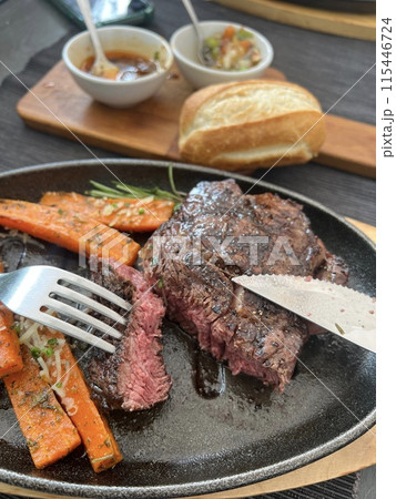 Grilled Steaks with spices rosemary and pepper on wooden board on black background. 115446724