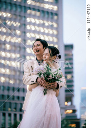 東京駅前撮り新郎にバックハグされる新婦 115447130