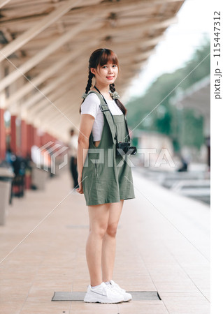 Portrait Young asian woman smiling tourist Traveler girl walking and with a holding the camera waits train travel journey is taken in railway platform Thailand, summer relax vacation Concept. Portrait Young asian woman smiling tourist Traveler girl walking and with a holding the camera waits train travel journey is taken in railway platform Thailand, summer relax vacation Concept. 115447312