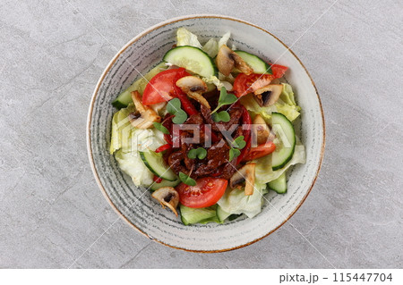 Asian beef salad with vegetables and nuts in a white bowl on a dark background. Asian food concept. Asian beef salad with vegetables and nuts in a white bowl on a dark background. Asian food concept. 115447704