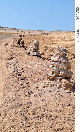 Close up of road in a desert area fenced with homemade pyramids made of stones.Vertical Close up of road in a desert area fenced with homemade pyramids made of stones.Vertical 115447880