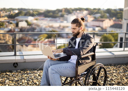 Caucasain man in wheelchair working on laptop outdoors Caucasain man in wheelchair working on laptop outdoors 115448120