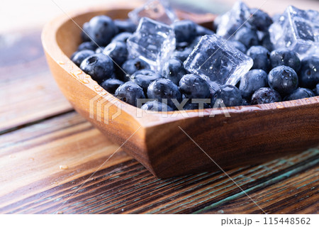 Fresh blueberries with ice cubes close-up on a wooden plate 115448562