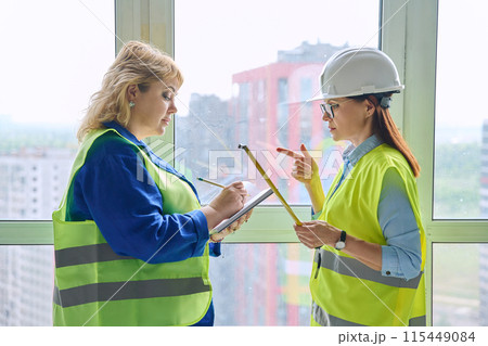 Two female industrial workers taking measurements of windows for decoration Two female industrial workers taking measurements of windows for decoration 115449084