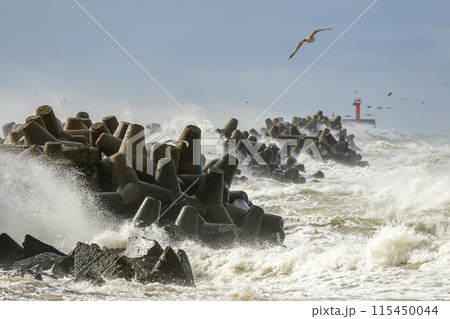 Hurricane storm at sea, high waves crashing against the concrete breakwaters of the port 115450044