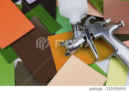 a paint spray gun at work at the workplace in the workshop. Paint samples. 115450242