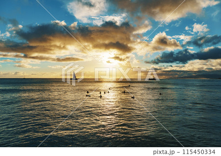 A group of people are enjoying a sunset swim in the ocean together 115450334