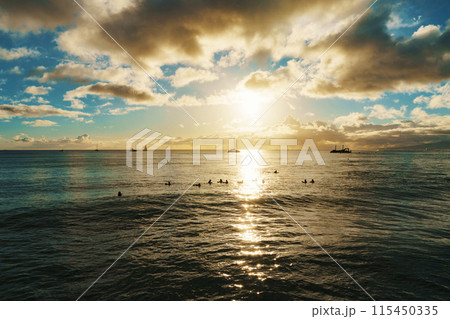 Sun sets, casting warm glow over ocean, boats float in distance Sun sets, casting warm glow over ocean, boats float in distance 115450335