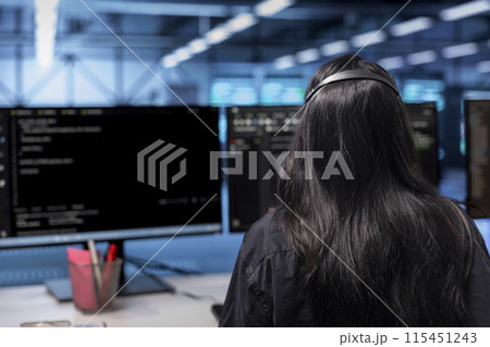 Software developer in server hub establishment ensuring data remains shielded from potential threats. Employee at PC desk safeguarding data center against unauthorized access 115451243