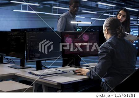 Computer scientist in server hub calling coworkers for help, trying to protect equipment from hacker. IT specialist in data center facility requesting assistance to fix security breach alert 115451281