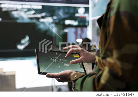 Military IT engineer collecting intelligence from world map projection, tablet connected to radar CCTV system to support soldiers in the field. Dispatch federal defense agency control room. Close up. Military IT engineer collecting intelligence from world map projection, tablet connected to radar CCTV system to support soldiers in the field. Dispatch federal defense agency control room. Close up. 115451647