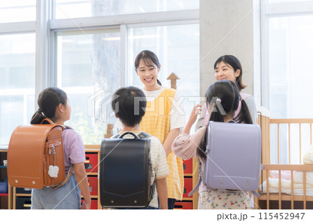 学童の先生とさようならをする小学生 放課後デイや学童などの教室で先生と会話するところ 学童の先生とさようならをする小学生 放課後デイや学童などの教室で先生と会話するところ 115452947