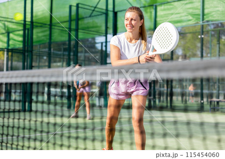European woman padel tennis player trains on the outdoor court European woman padel tennis player trains on the outdoor court 115454060