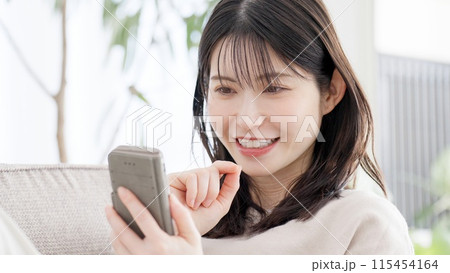 リビングでスマホを見る女性 115454164