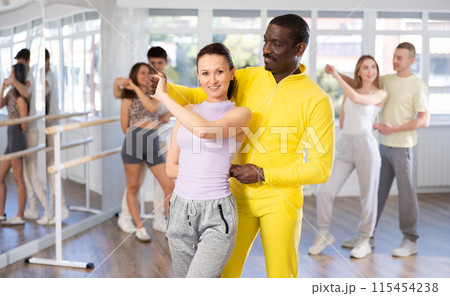 Middle-aged man and woman practicing waltz dance in pair in training hall Middle-aged man and woman practicing waltz dance in pair in training hall 115454238
