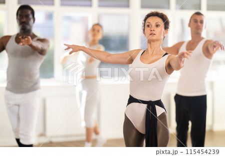 Graceful woman leading ballet class with adult amateur dancers Graceful woman leading ballet class with adult amateur dancers 115454239